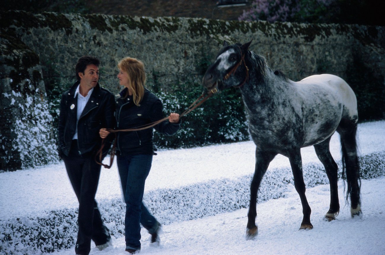 Paul McCartney and his wife, Linda, walking a horse in the snow during Christmas time, 1979.