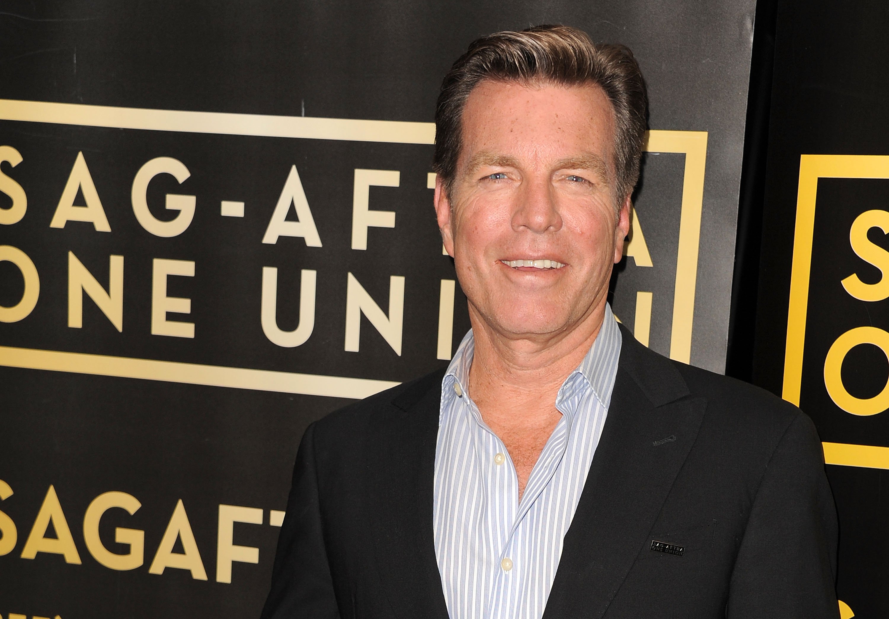 'The Young and the Restless' actor Peter Bergman wearing a black suit and blue and white striped shirt.