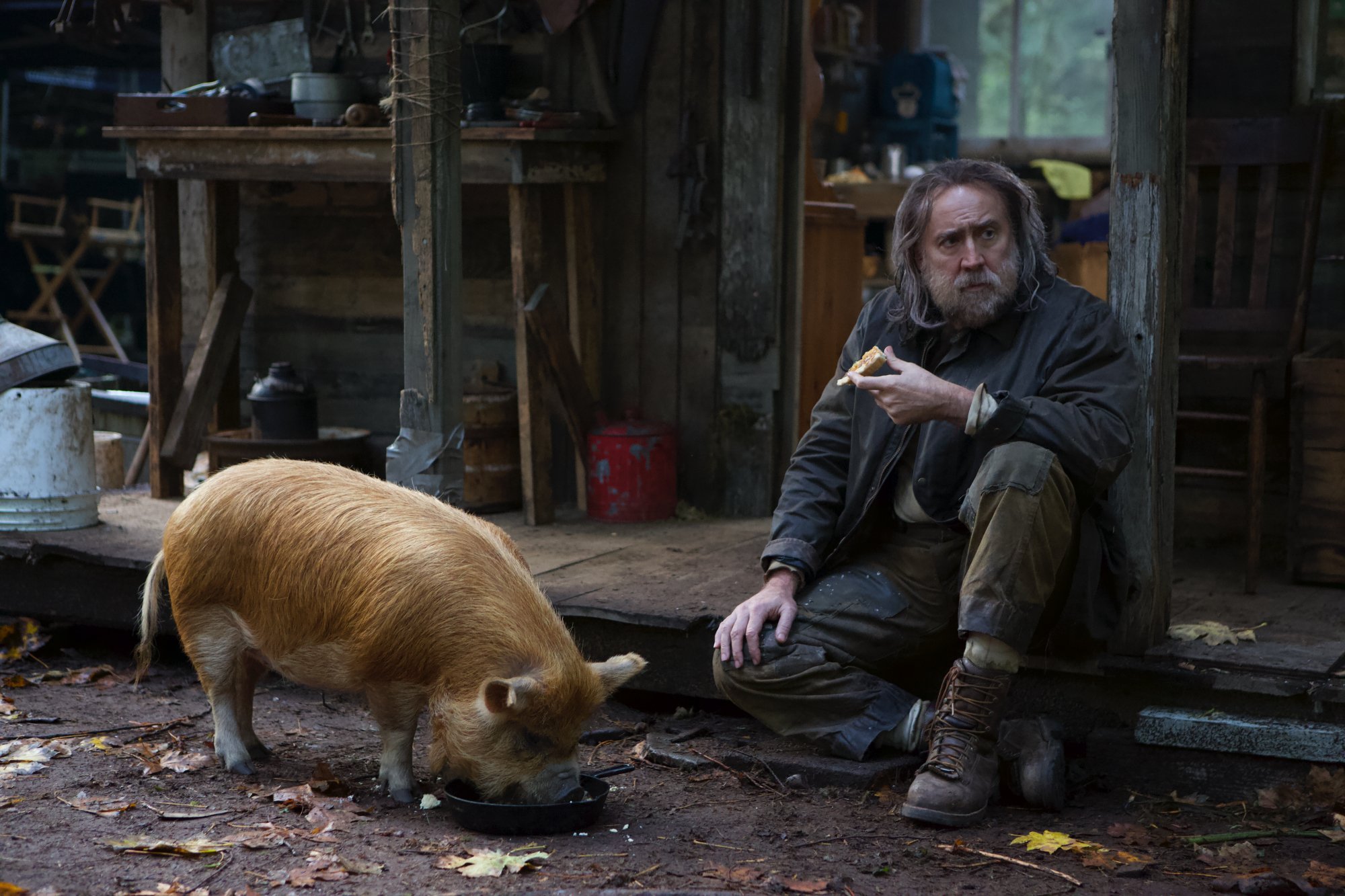 'Pig' Nicolas Cage as Rob sitting next to his pig and eating