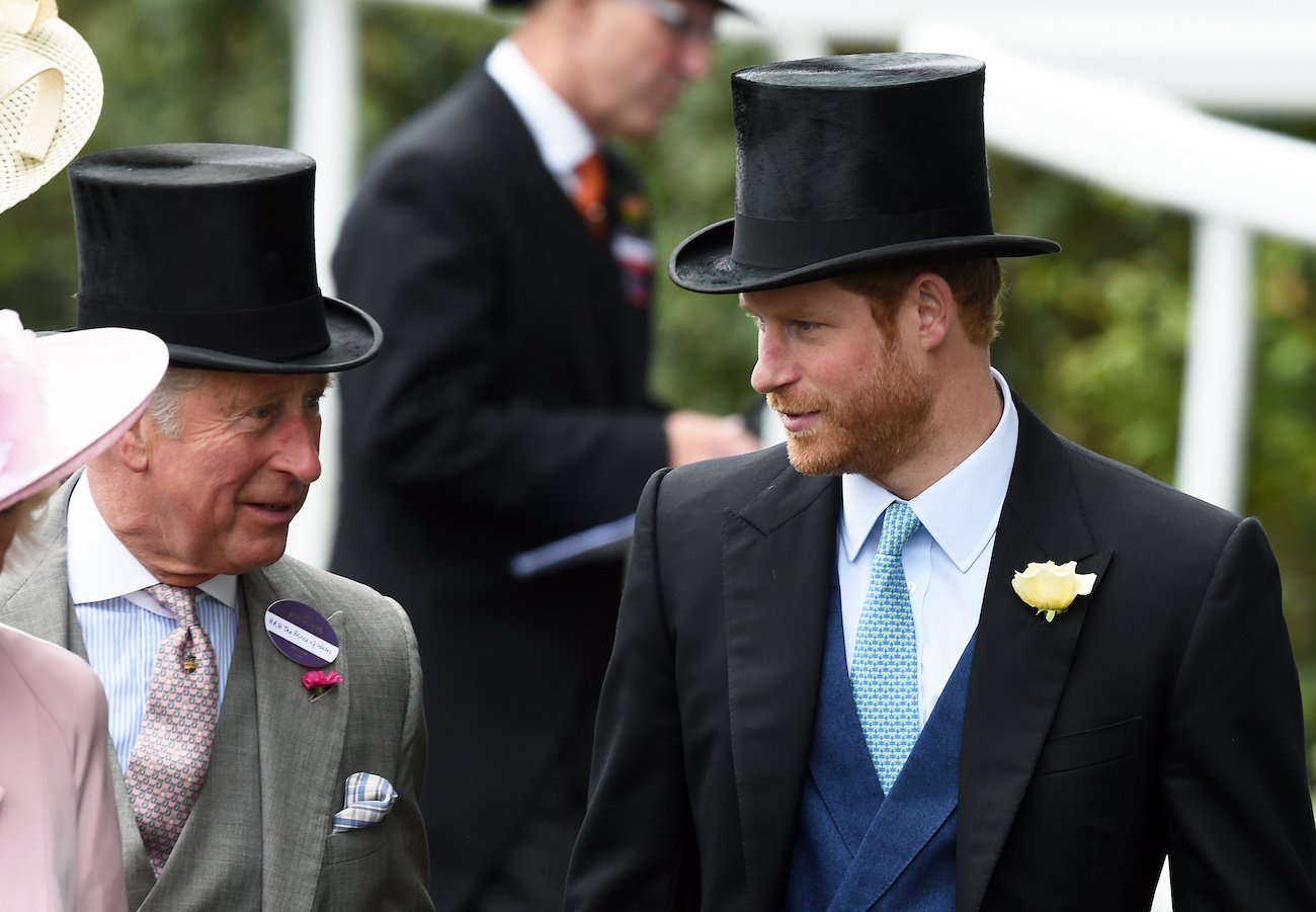 Prince Charles and Prince Harry look at each other while wearing top hats
