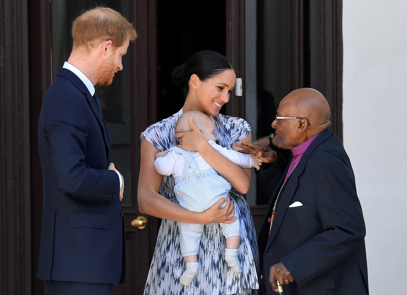 Prince Harry and Meghan Markle, who is holding son Archie, interacting with Desmond Tutu