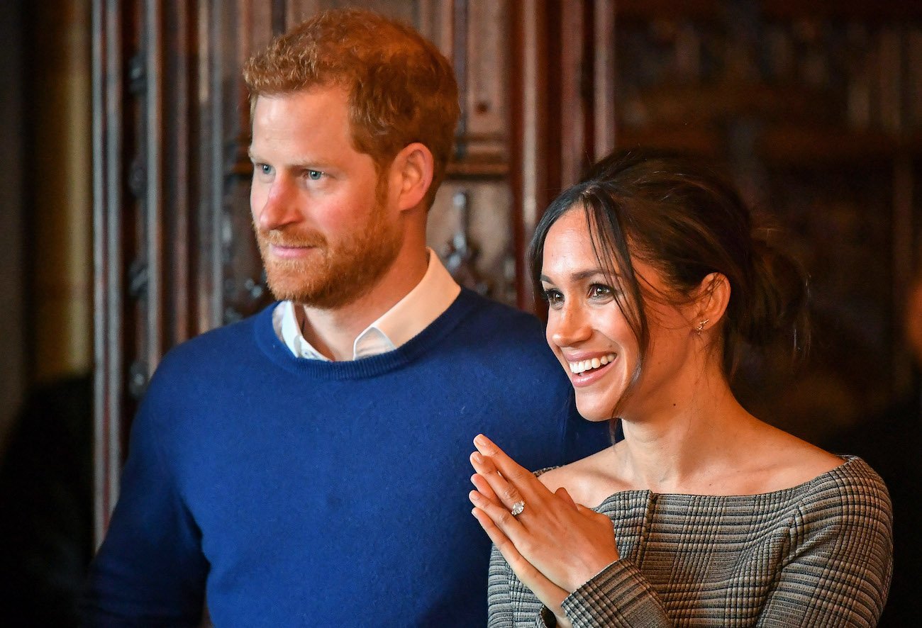 Prince Harry and Meghan Markle smile as they stand next to each other