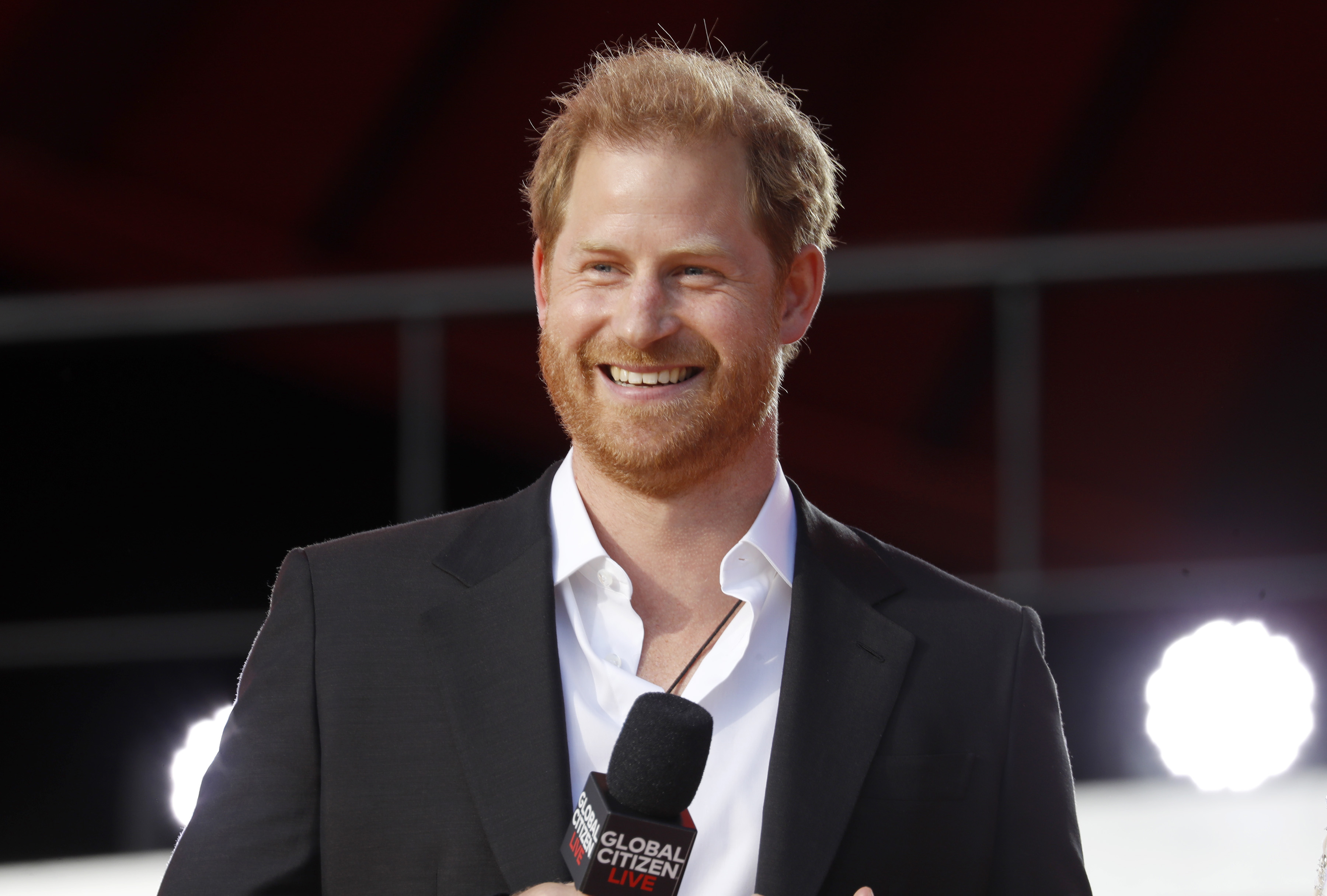 Prince Harry smiling as he speaks onstage during Global Citizen Live