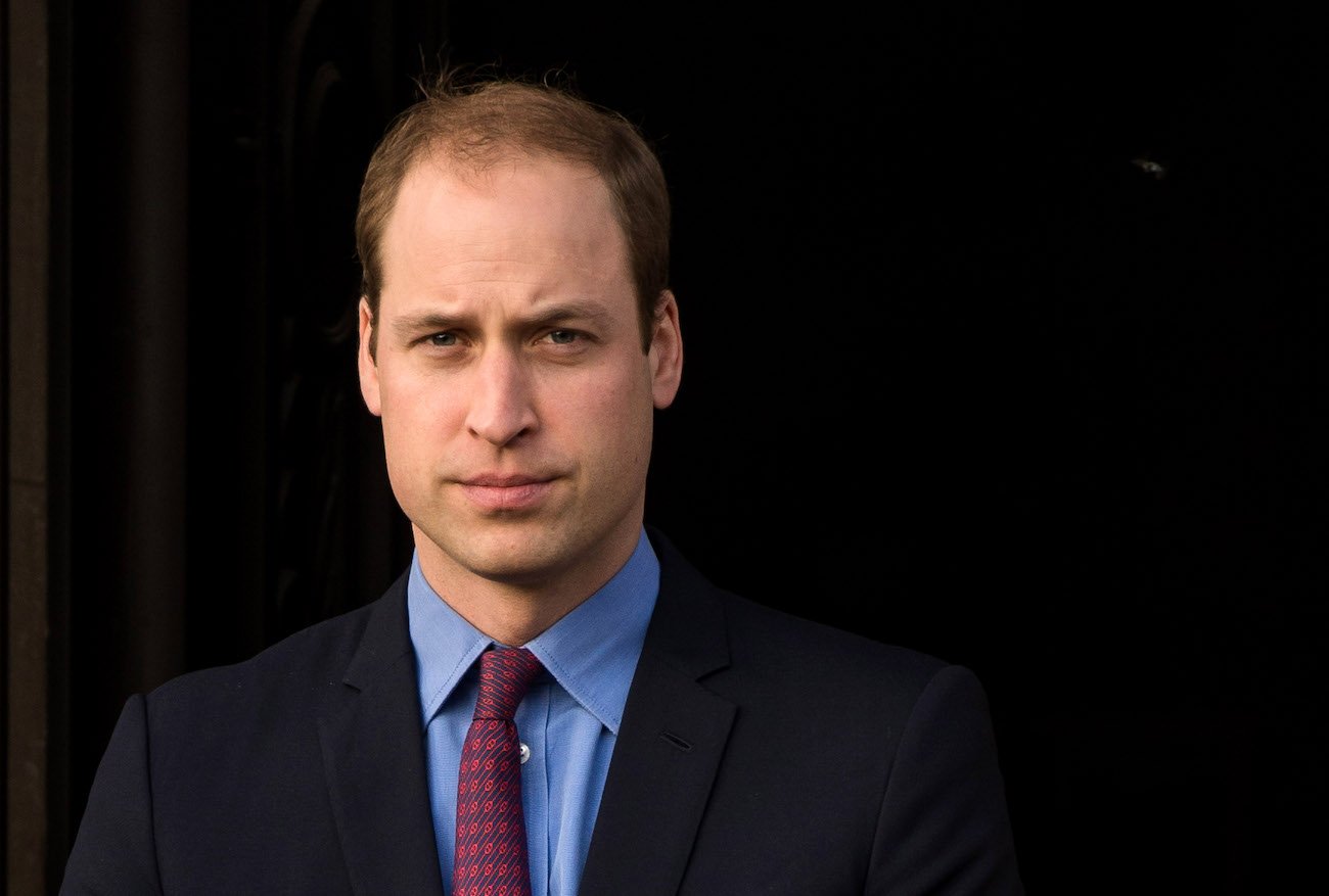 Prince William looking on in front of a dark background