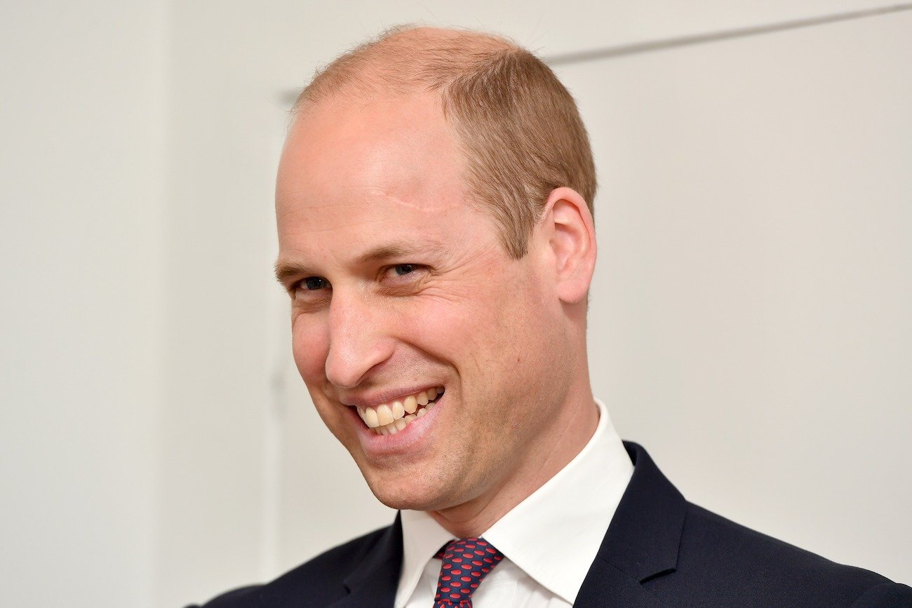 Prince William smiling, wearing a suit