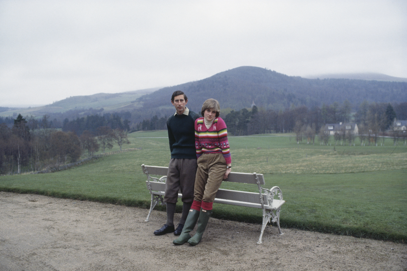 Prince Charles and Princess Diana outdoor, leaning against a bench