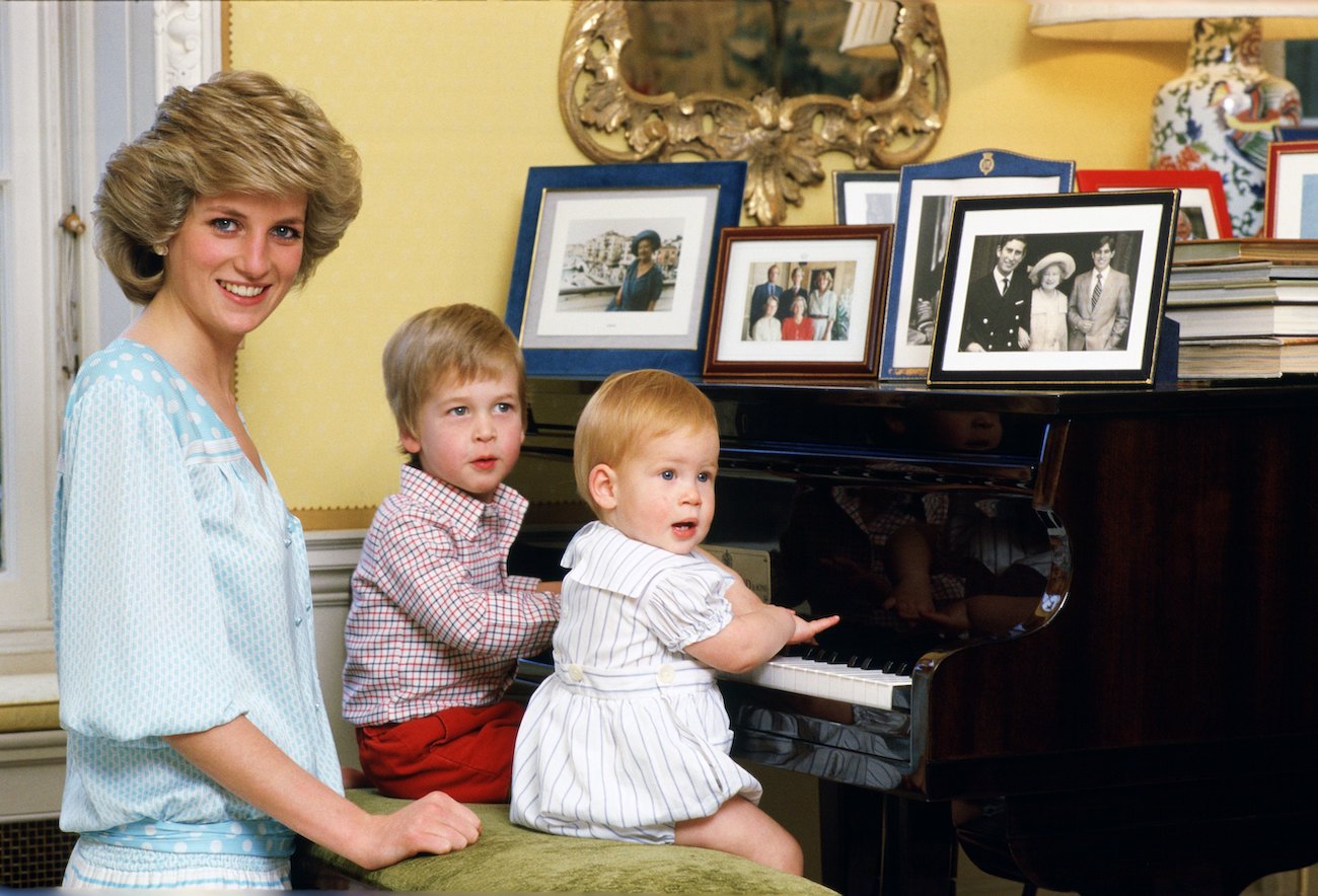 Princess Diana looking on while Prince William and Prince Harry are sitting at piano