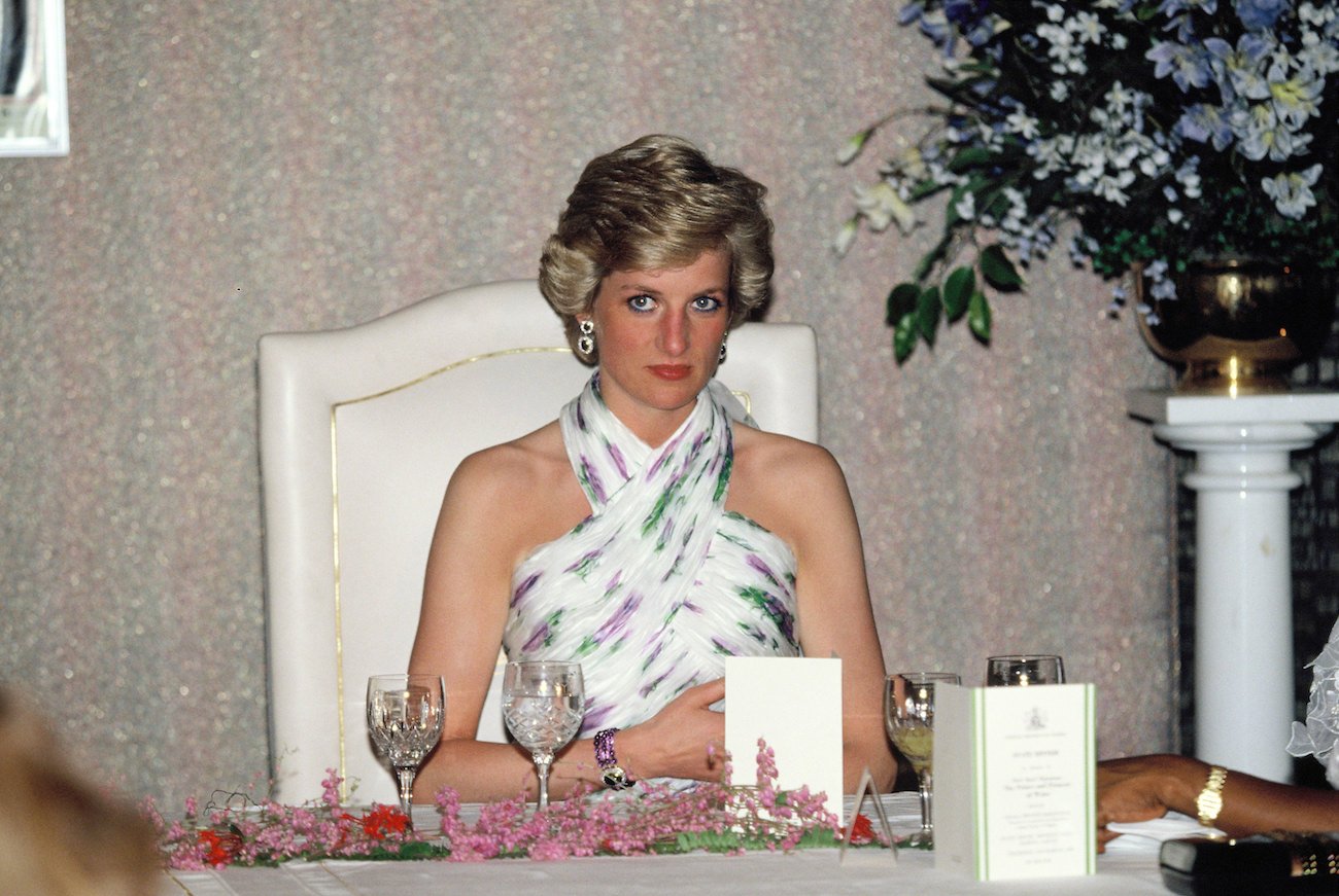Princess Diana wearing a halter dress at a dining table