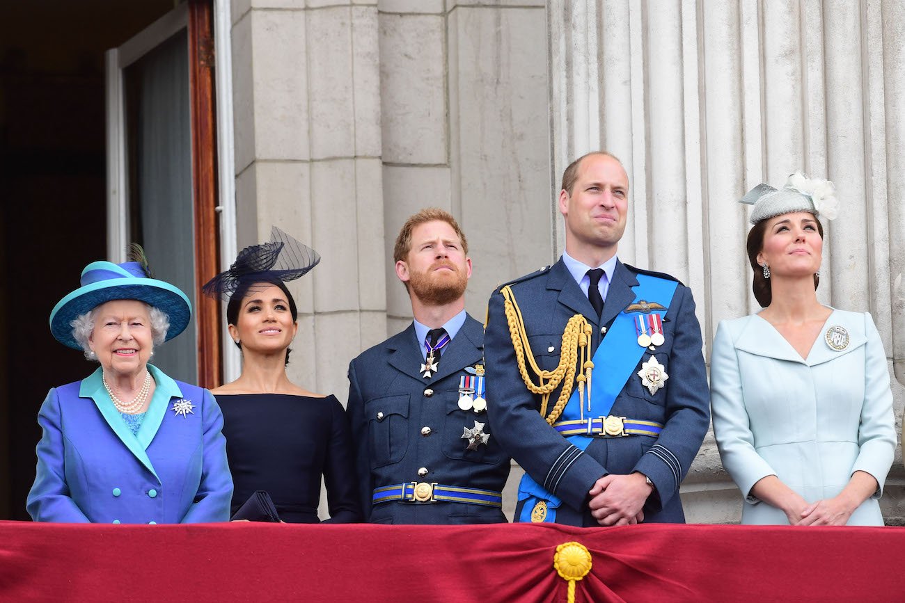 Queen Elizabeth II smiles as she stands next to Meghan Markle, Prince Harry, Prince William, and Kate Middleton on the balcony of Buckingham Palace