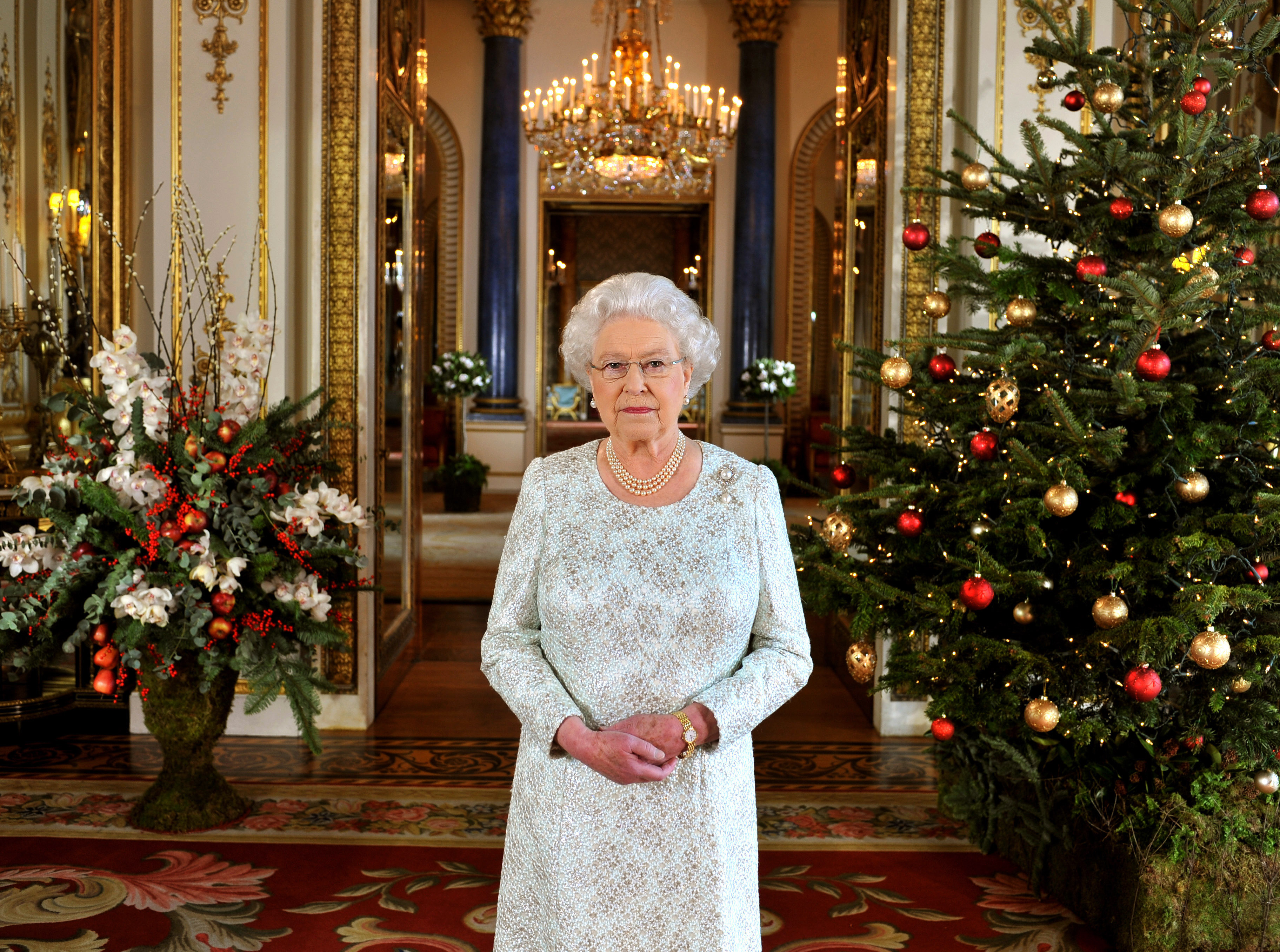 Queen Elizabeth II standing next to decorated trees as she records her Christmas message to the Commonwealth