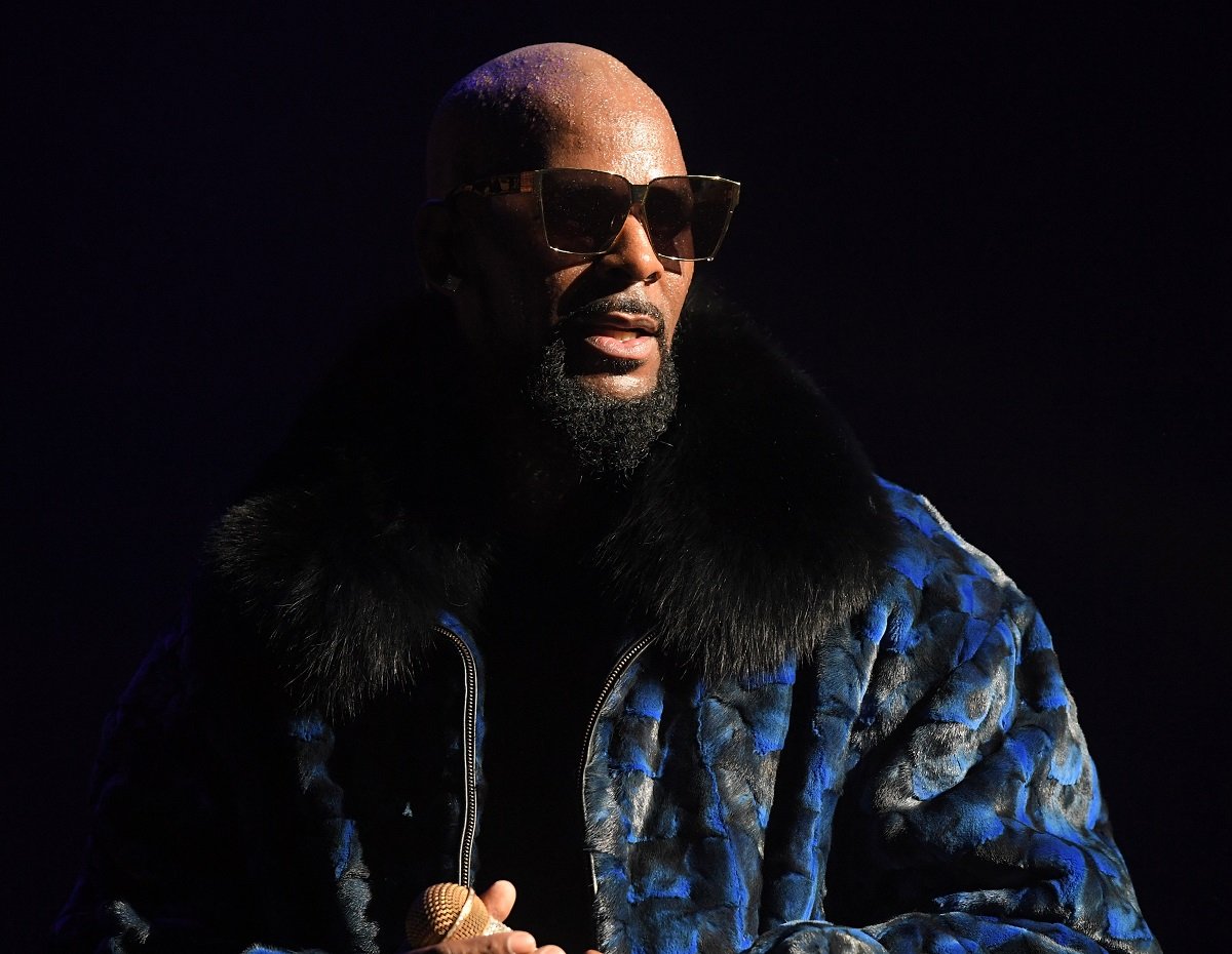 R. Kelly posing in a coat while wearing sunglasses.