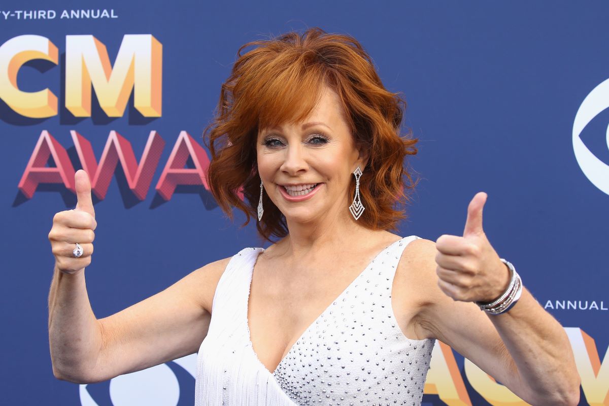 Reba McEntire dressed in white giving two thumbs up