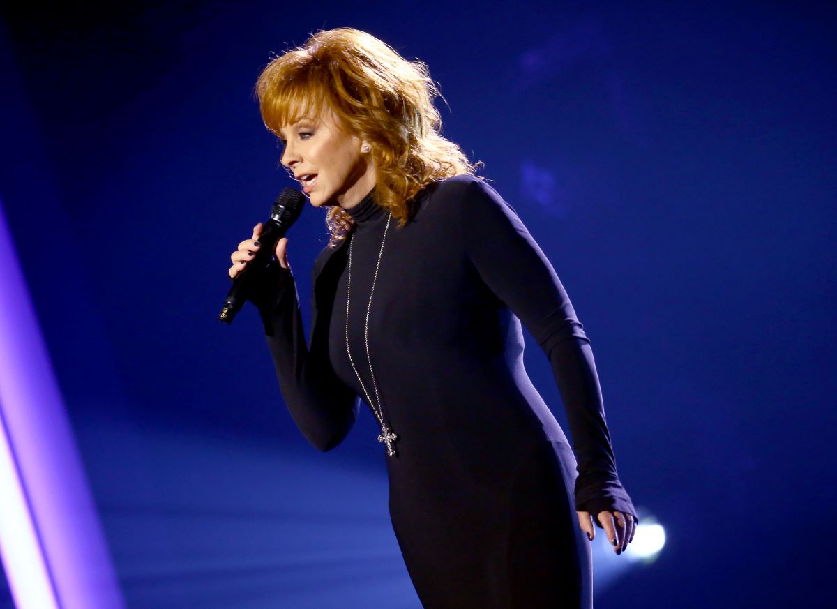 Reba McEntire in a black dress singing into a microphone