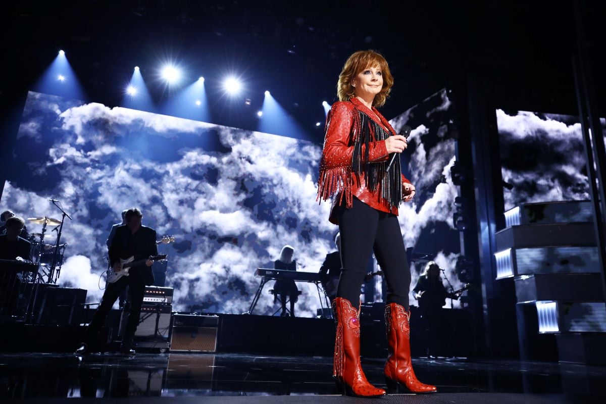 Reba McEntire in a jacket with fringe sleeves and cowboy boots