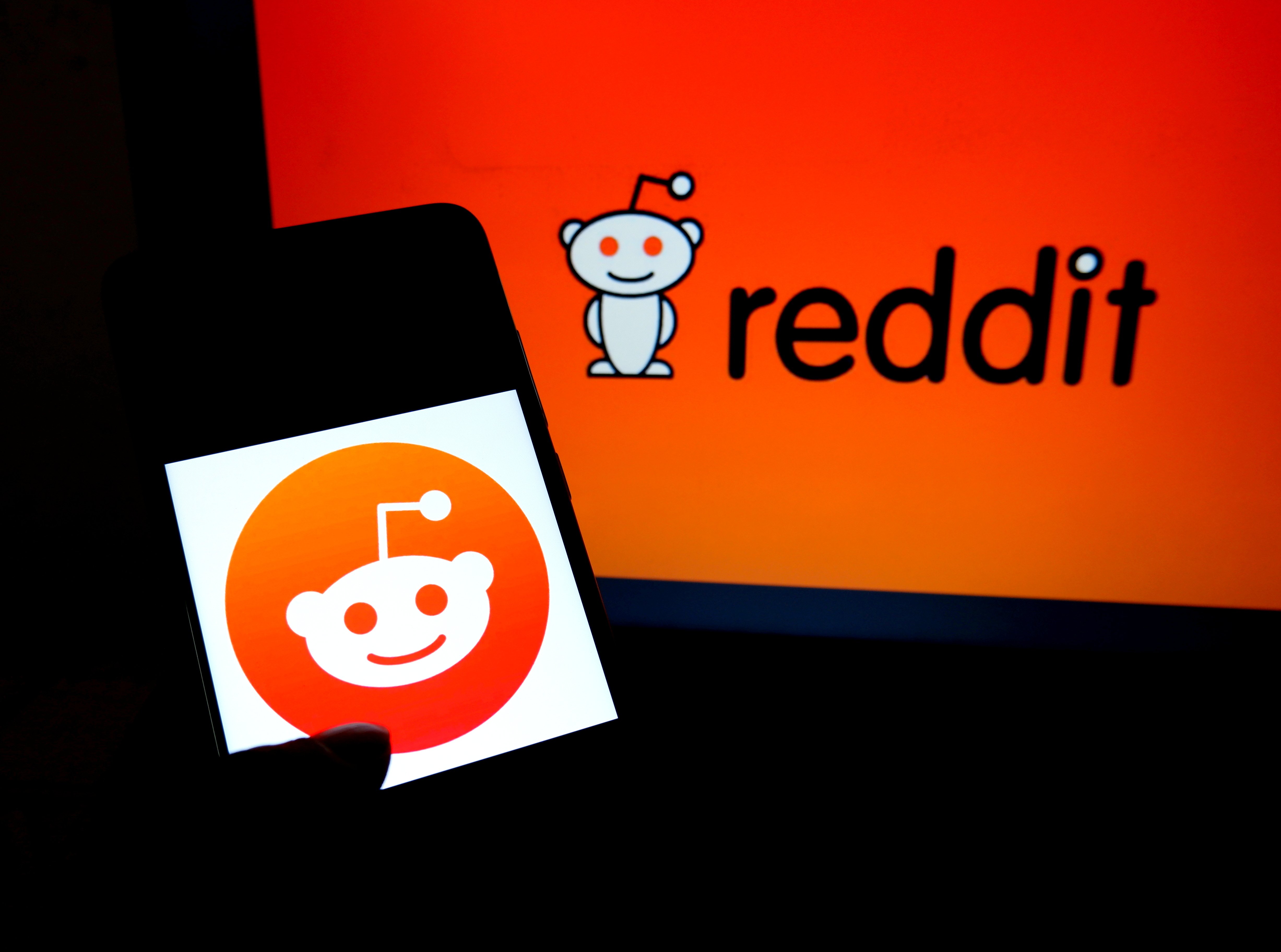 The logo of social news aggregate, Reddit, is seen on a computer and a smartphone