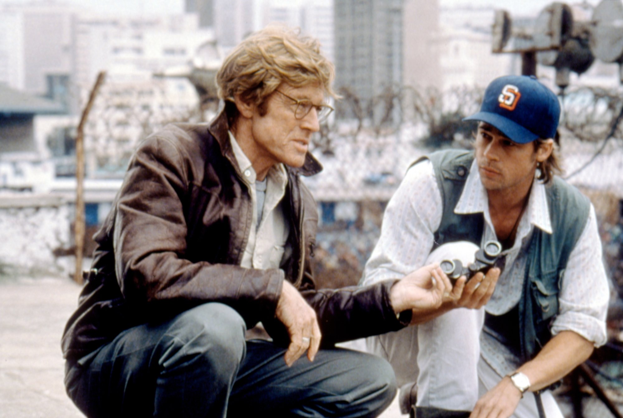 Robert Redford as Nathan Muir and Brad Pitt as Tom Bishop acting in 'Spy Game' handing binoculars