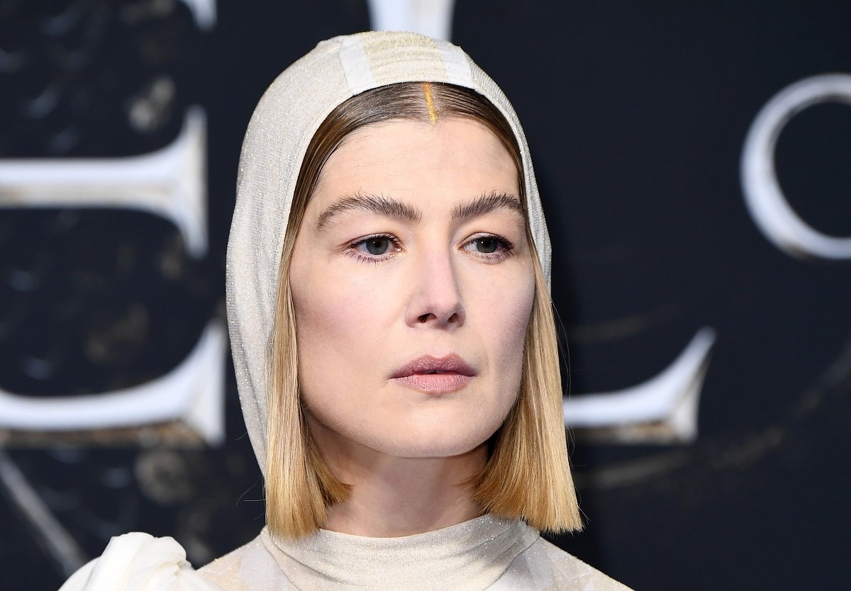 Rosamund Pike posing in a white dress.