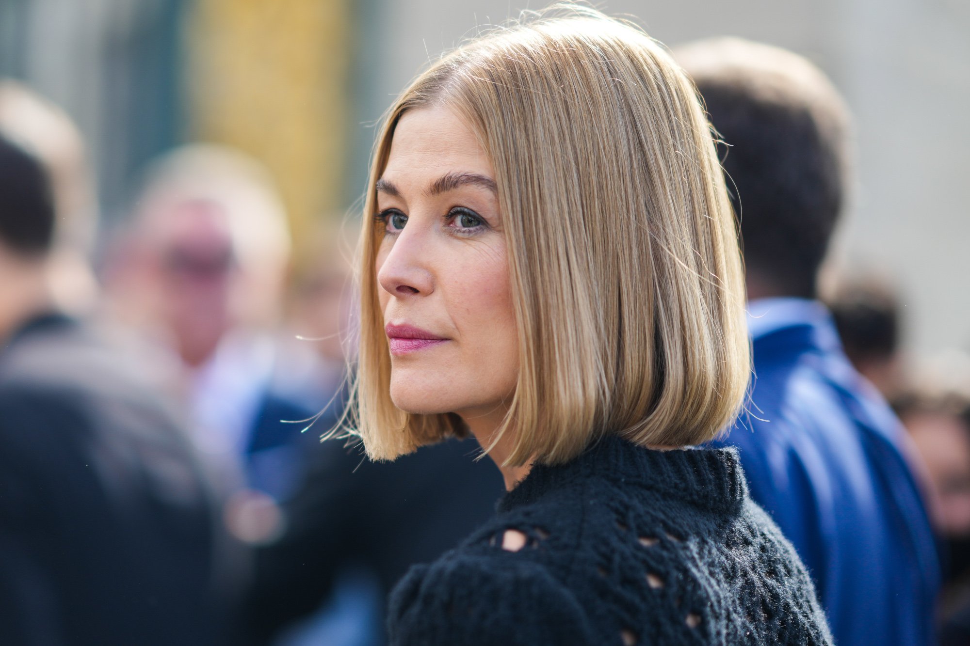 'The Wheel of TIme' and 'Gone Girl' star Rosamund Pike. Her blonde hair is down, and she's looking over her shoulder.