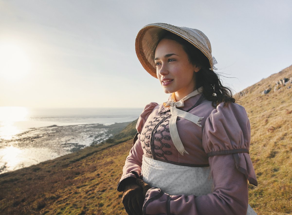 Rose Williams as Charlotte Heywood, standing on a bluff and wearing a bonnet, in 'Sanditon' Season 1