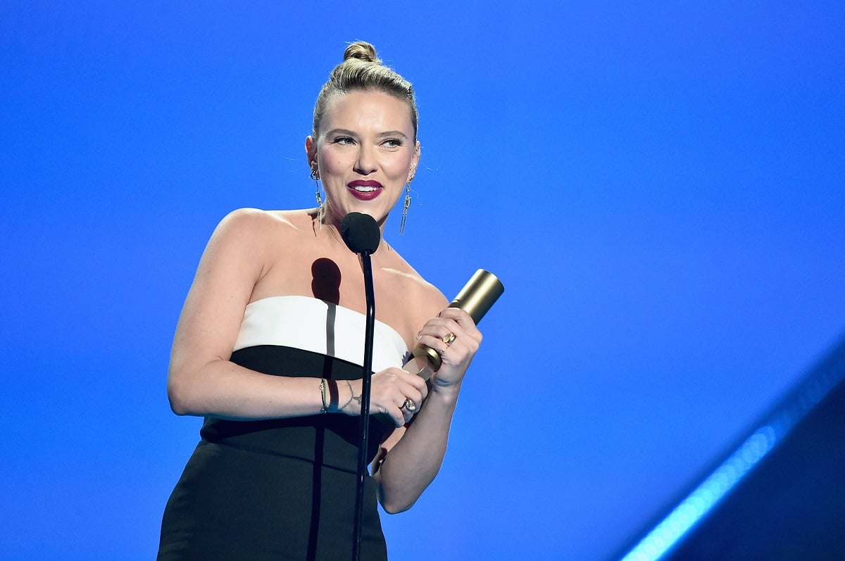 Scarlett Johansson holding a People's Choice award while wearing a dress.