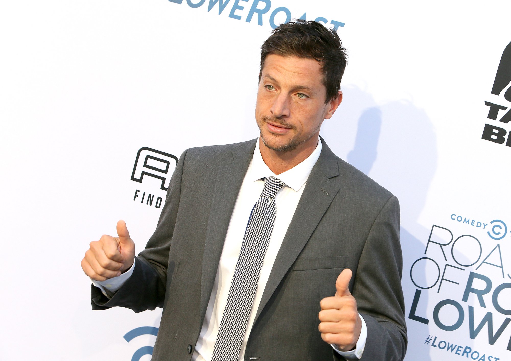 'Scary Movie 3' actor Simon Rex holding two thumbs up in front of a step and repeat