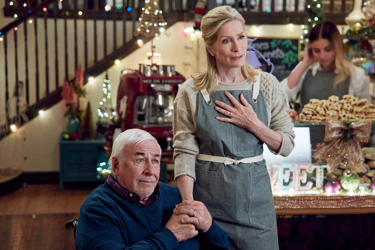 Anna Holbrook, wearing an apron, holding Jim Byrnes hand in 'Sister Swap: A Hometown Holiday'