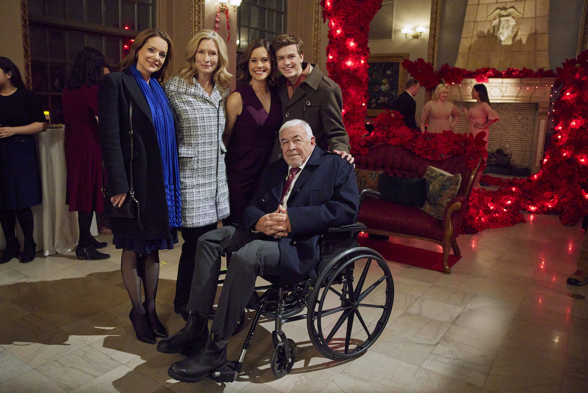 Kimberly Williams-Paisley, Anna Holbrook, Ashley Williams, and Jacob Buster standing behind Jim Byrnes, who is in a wheelchair, in 'Sister Swap: Christmas in the City'