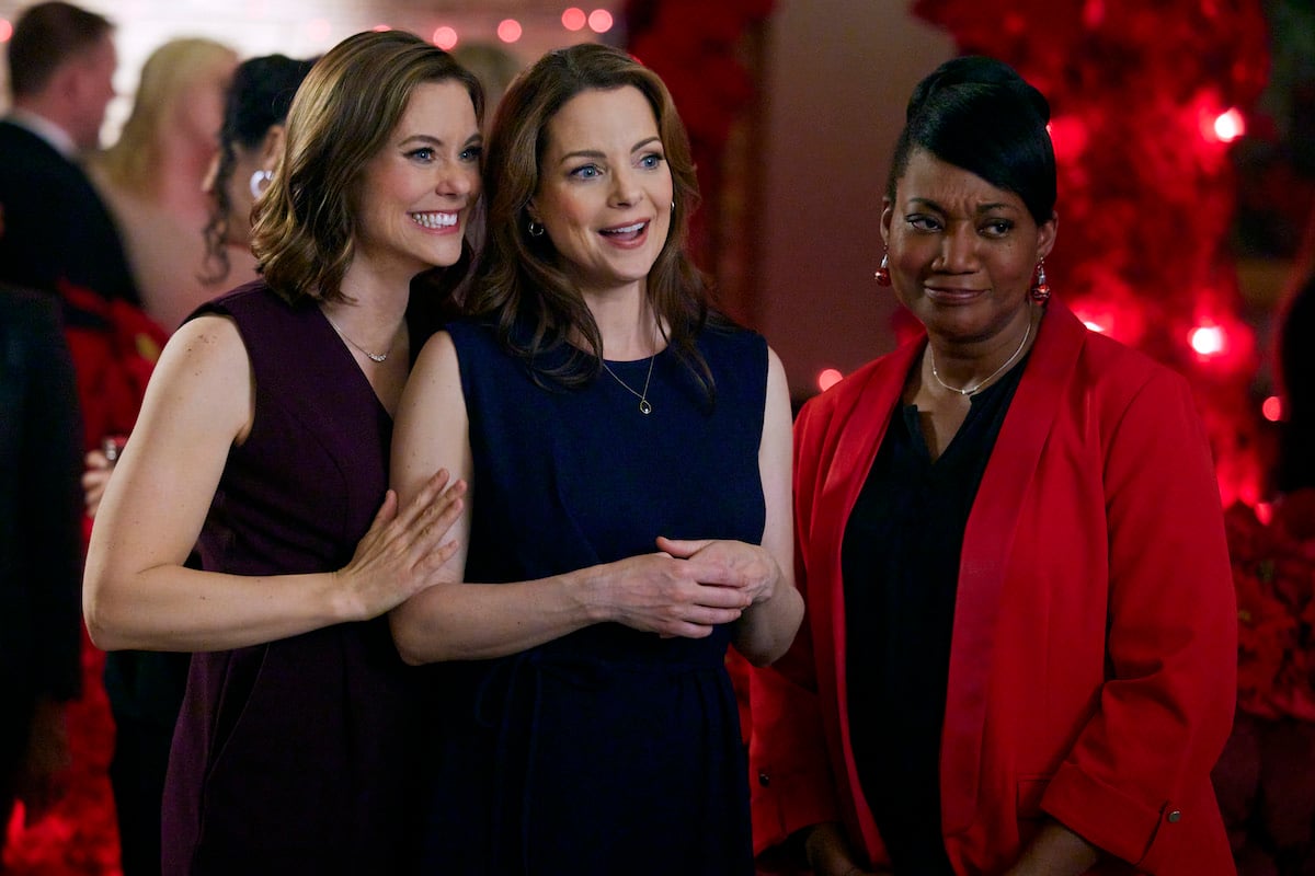 Ashley Williams and Kimberly Wiliams-Paisley, both in black dresses, standing next to a Yolanda Strange in a red jacket in 'Sister Swap: Christmas In the City'