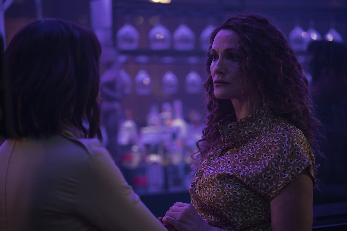 A woman talking to another person in a dimly lit bar in Netflix's 'Stay Close'