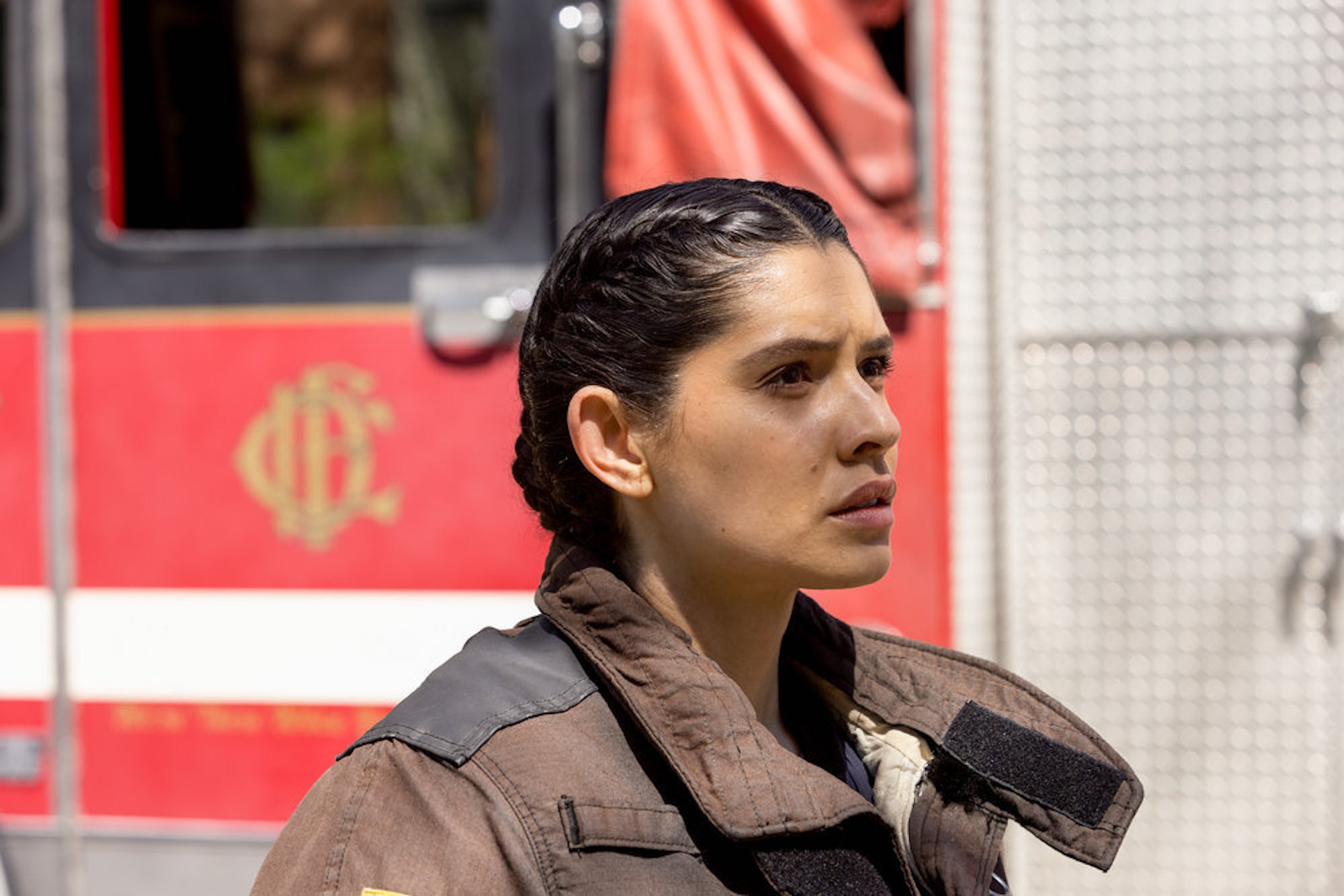 A close-up of Stella Kidd in a firefighting uniform against a fire truck in 'Chicago Fire'