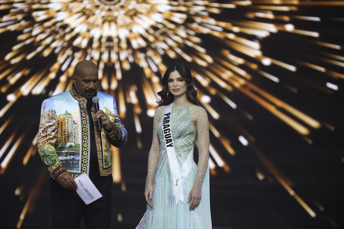 Host Steve Harvey holding a microphone and standing next to Miss Paraguay Nadia Ferreira at the 70th Miss Universe pageant