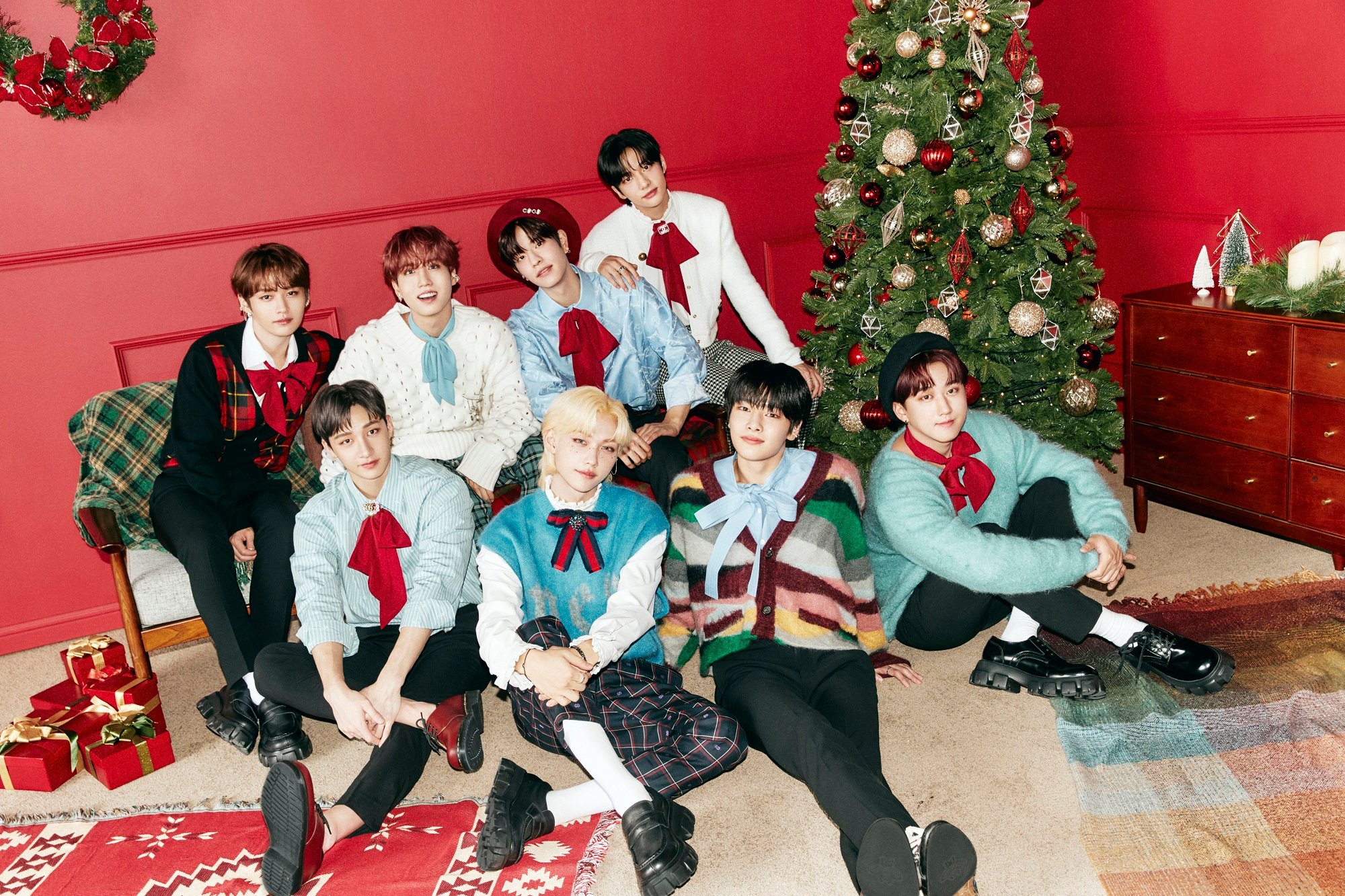 The members of the K-pop group Stray Kids pose with Christmas-themed decor