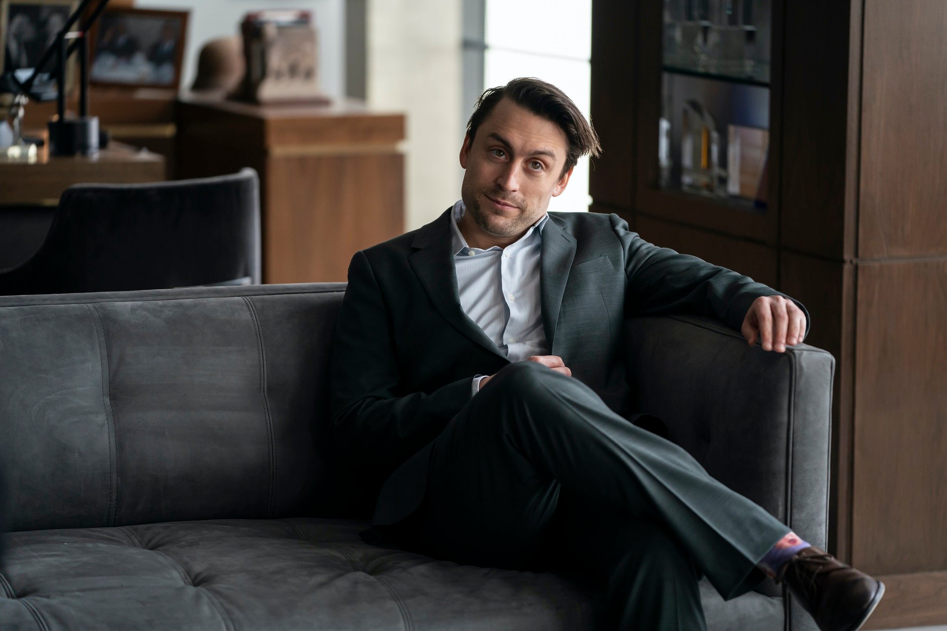 'Succession' cast member Kieran Culkin sitting down portraying Roman Roy