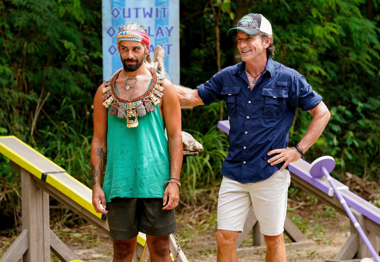 Ricard Foye on 'Survivor 41' stands wearing the immunity necklace next to Jeff Probst.