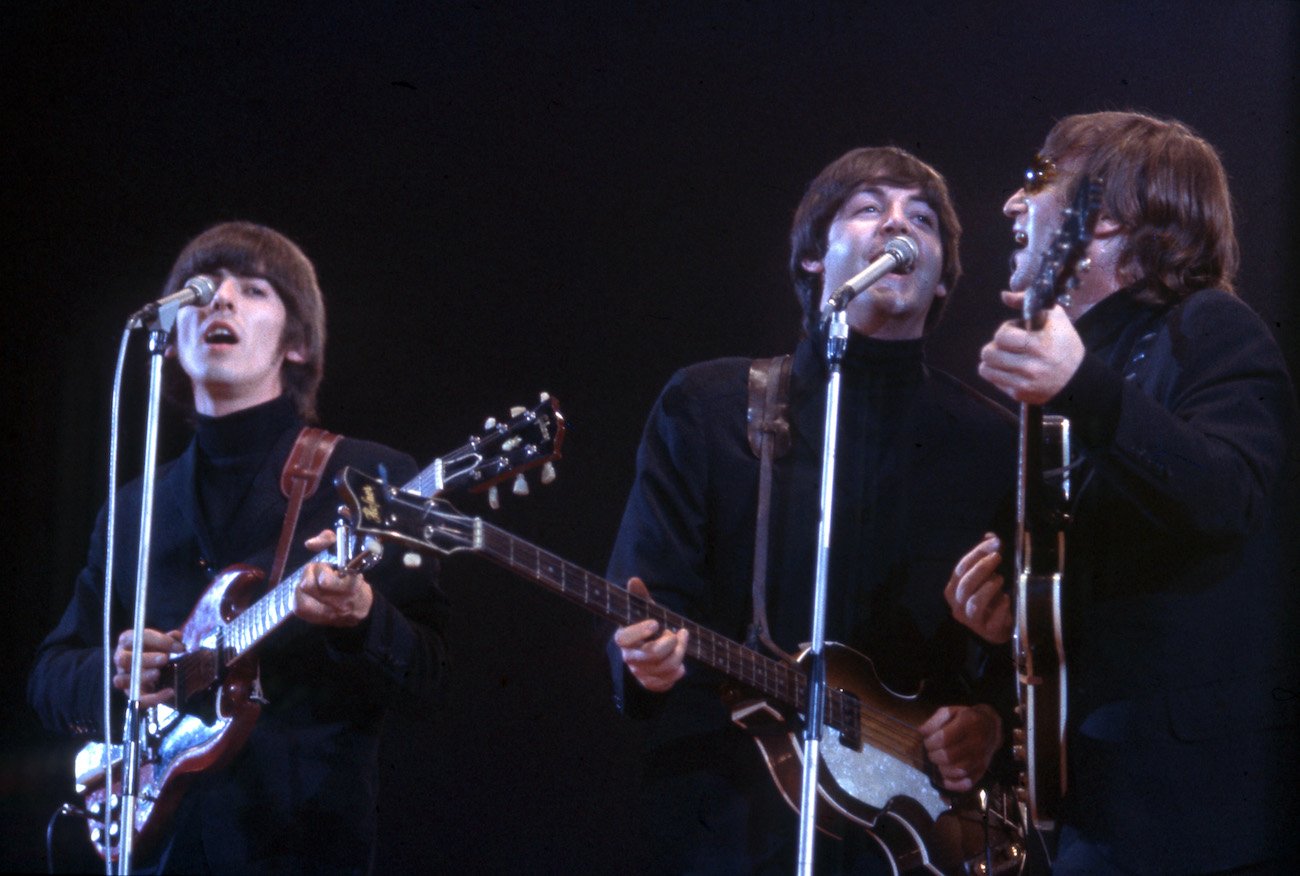 George Harrison, Paul McCartney, and John Lennon of The Beatles wearing black while performing in Wembley, 1966.
