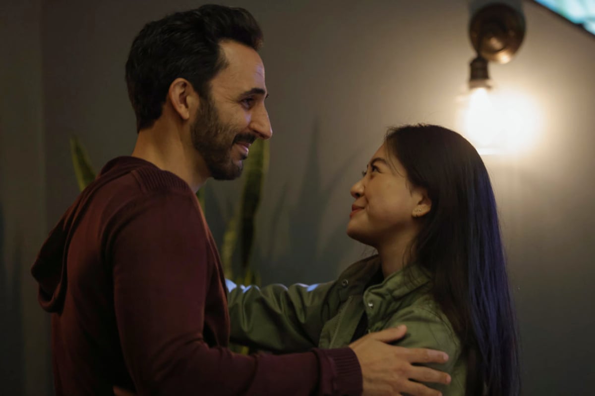 mir Arison as Aram Mojtabai and Laura Sohn as Agent Alina Park in The Blacklist Season 9. Aram and Park embrace each other and smile.