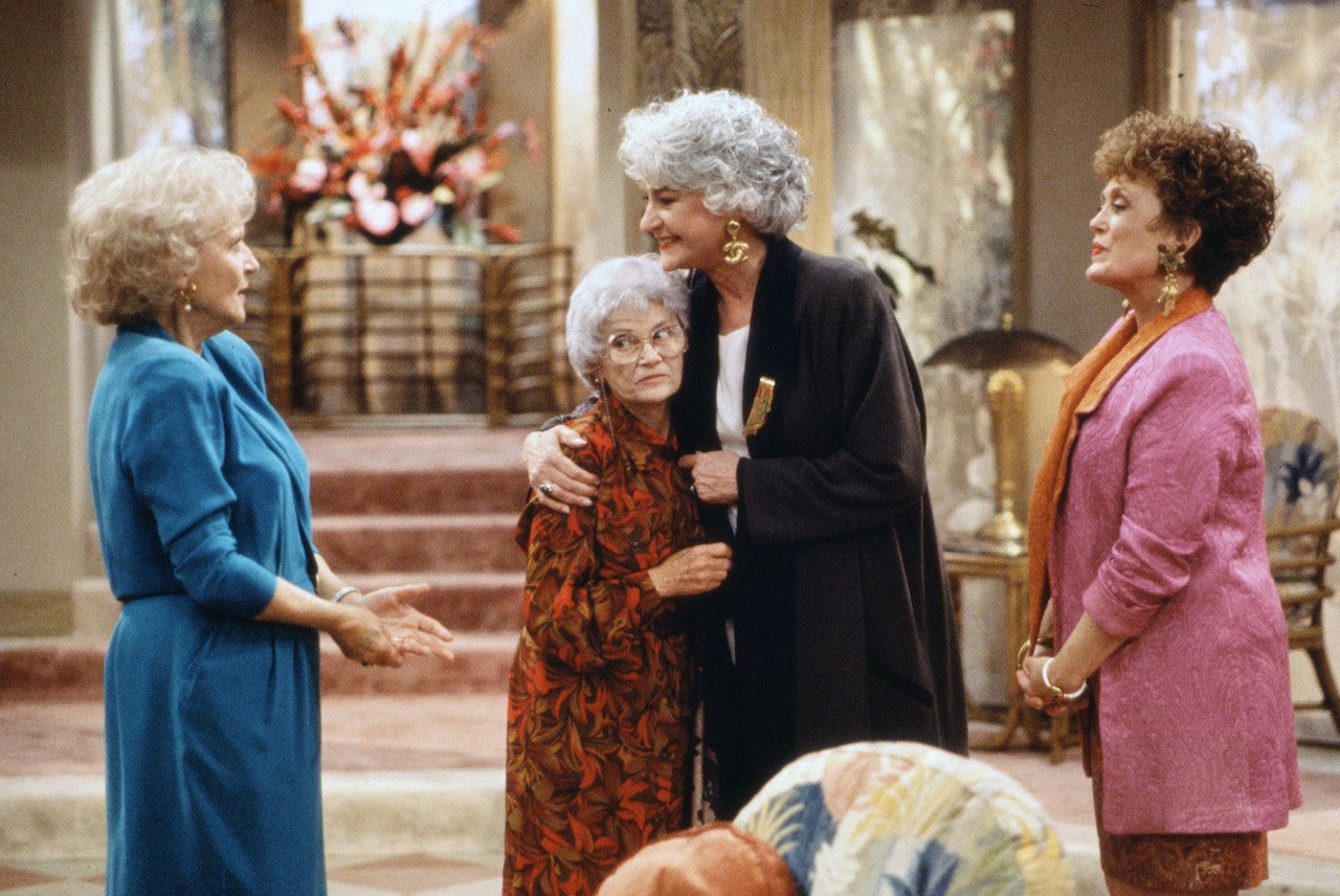 Betty White as Rose Nylund, Estelle Getty as Sophia Petrillo, Bea Arthur as Dorothy Zbornak Hollingsworth and Rue McClanahan as Blanch Devereaux stand together in a hotel lobby in 'THE GOLDEN PALACE'