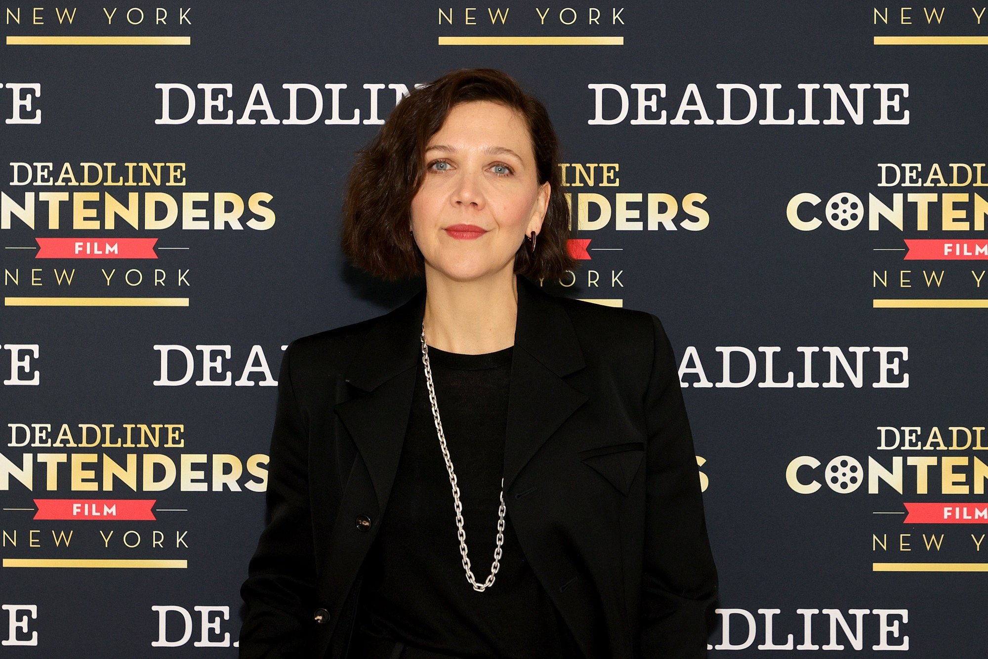 'The Lost Daughter' Maggie Gyllenhaal standing in front of a Deadline step and repeat