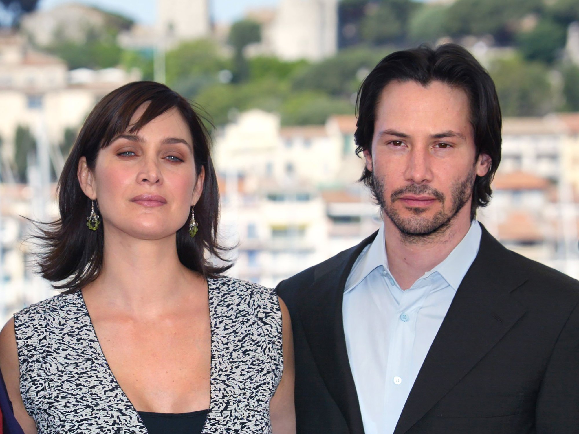 'The Matrix Resurrections' Carrie-Anne Moss and Keanu Reeves during the 56th Cannes film festival in front of white buildings