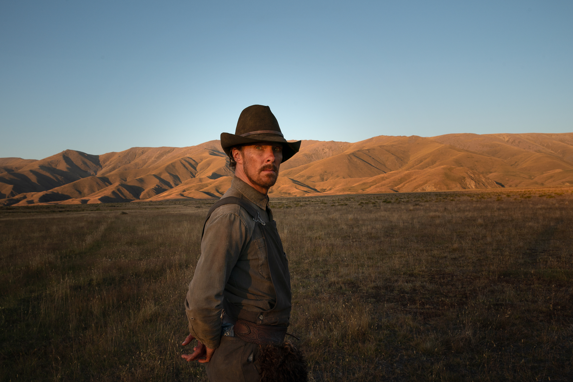 'The Power of the Dog' star Benedict Cumberbatch as Phil Burbank standing in a field in rancher clothes