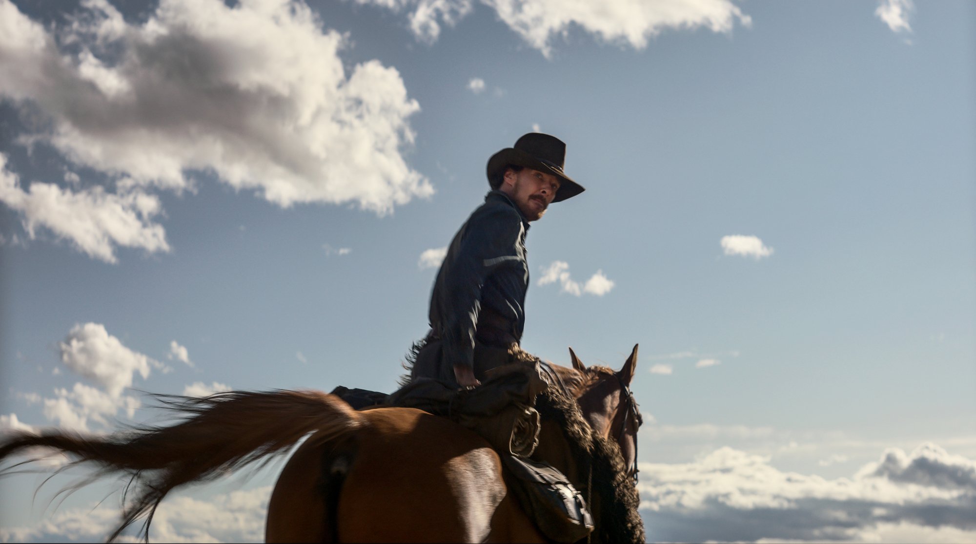 'The Power of the Dog' actor Benedict Cumberbatch as Phil Burbank riding on a horse looking back