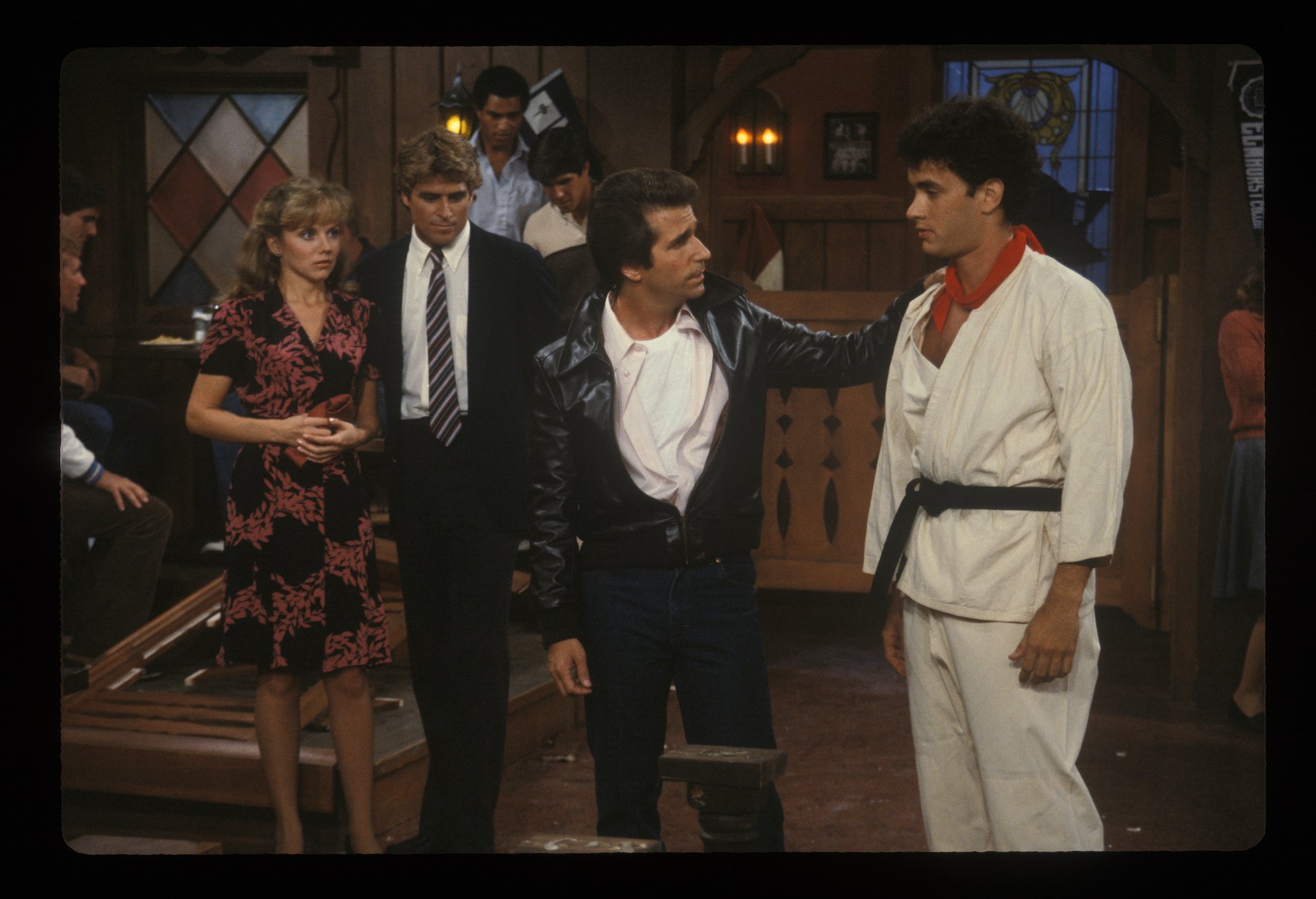 Tom Hanks wears a Karate gi and blackbelt while Henry Winkler puts his hand on his shoulder