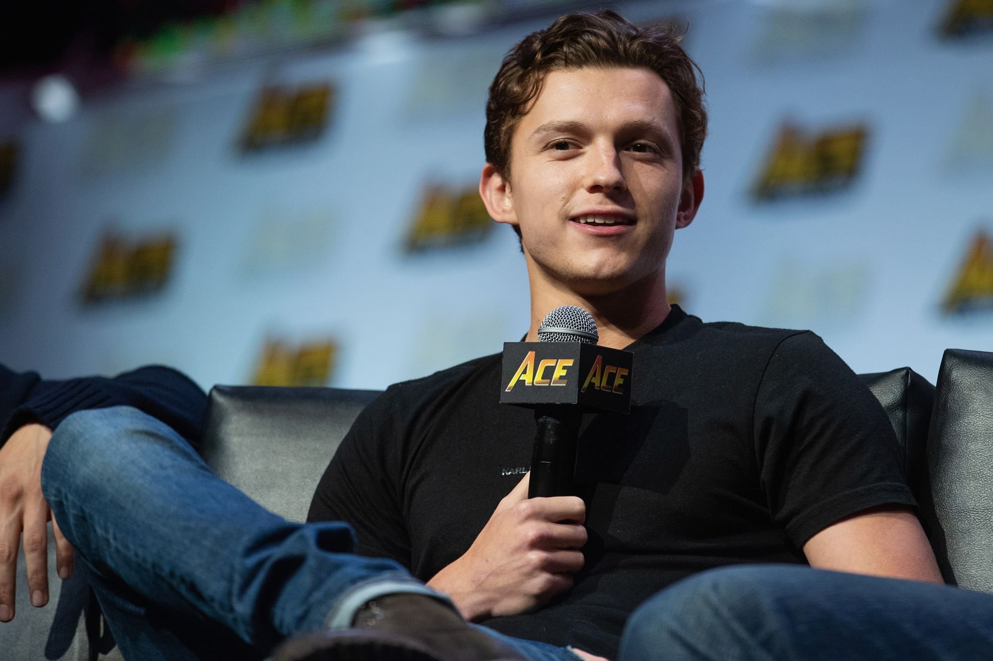 'Spider-Man: No Way Home' star Tom Holland wears a black shirt and jeans. Holland starred alongside Chris Evans in 'Captain America: Civil War.'