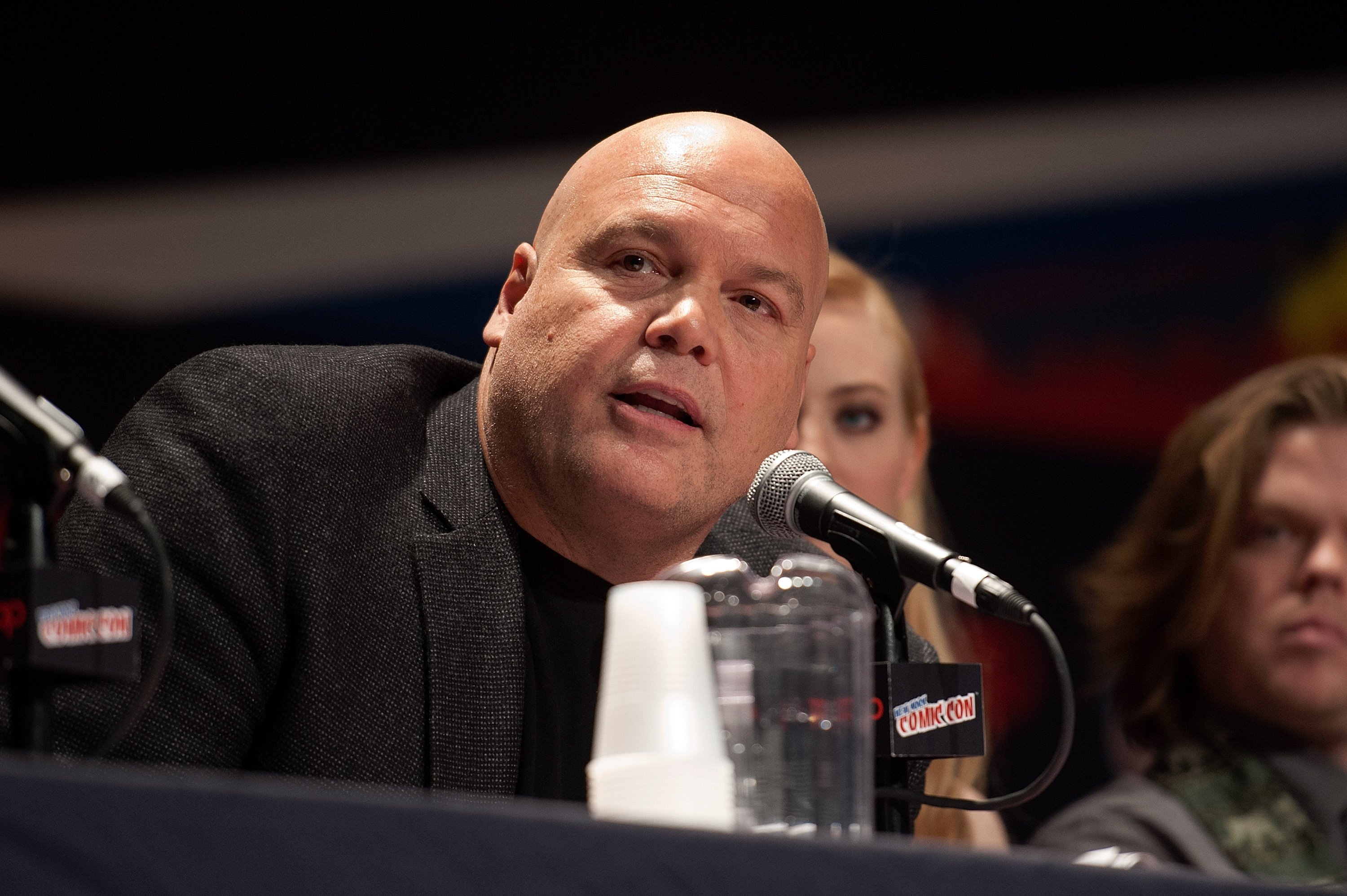 Vincent D'Onofrio, who may reprise his role as Kingpin and be Echo's uncle in 'Hawkeye,' speaks onstage during a panel. The actor wears a gray suit jacket over a black shirt.