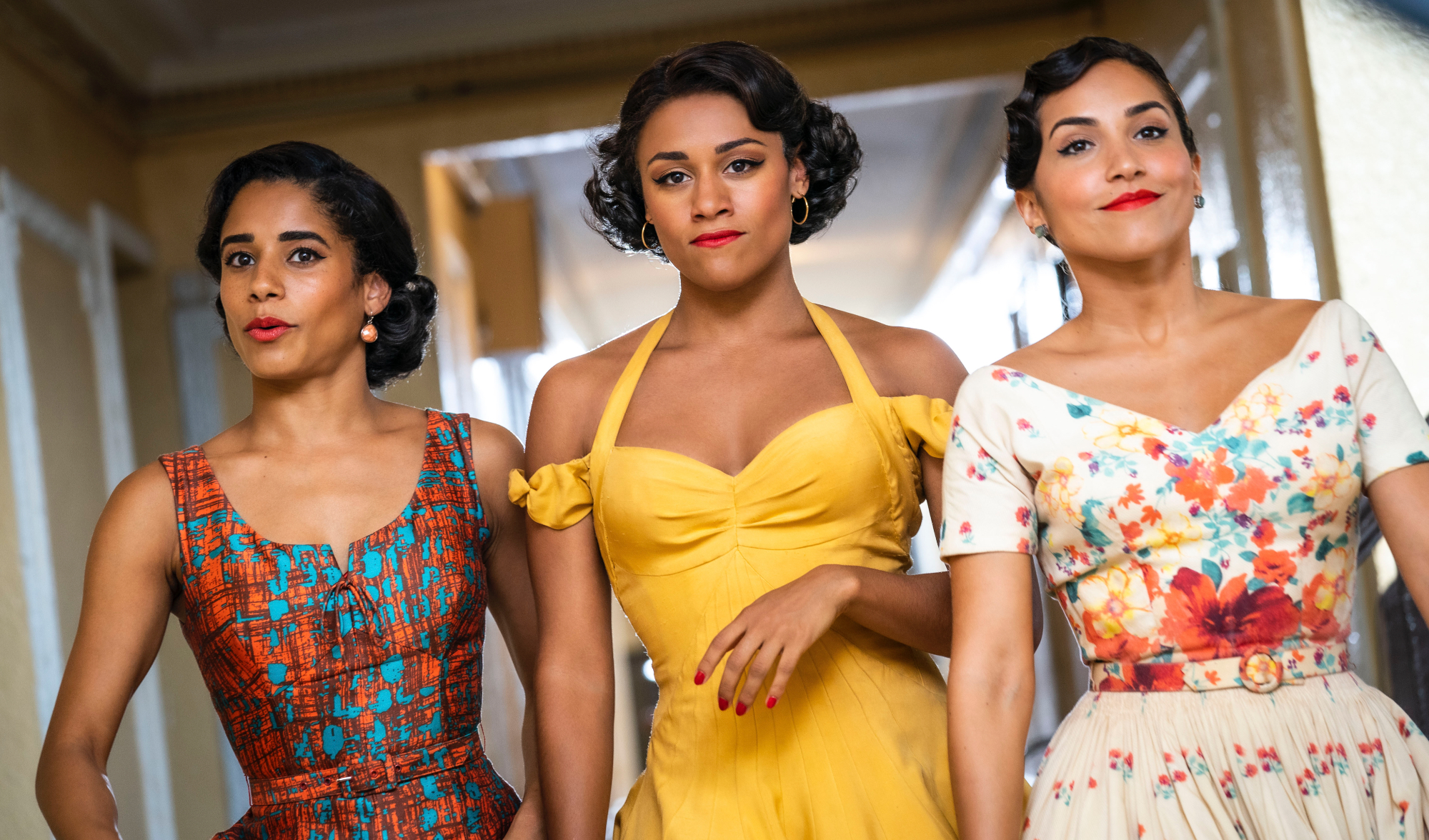'West Side Story' Ilda Mason as Luz, Ariana DeBose as Anita, and Ana Isabelle as Rosalia in article about box office wearing dresses, walking down a hallway