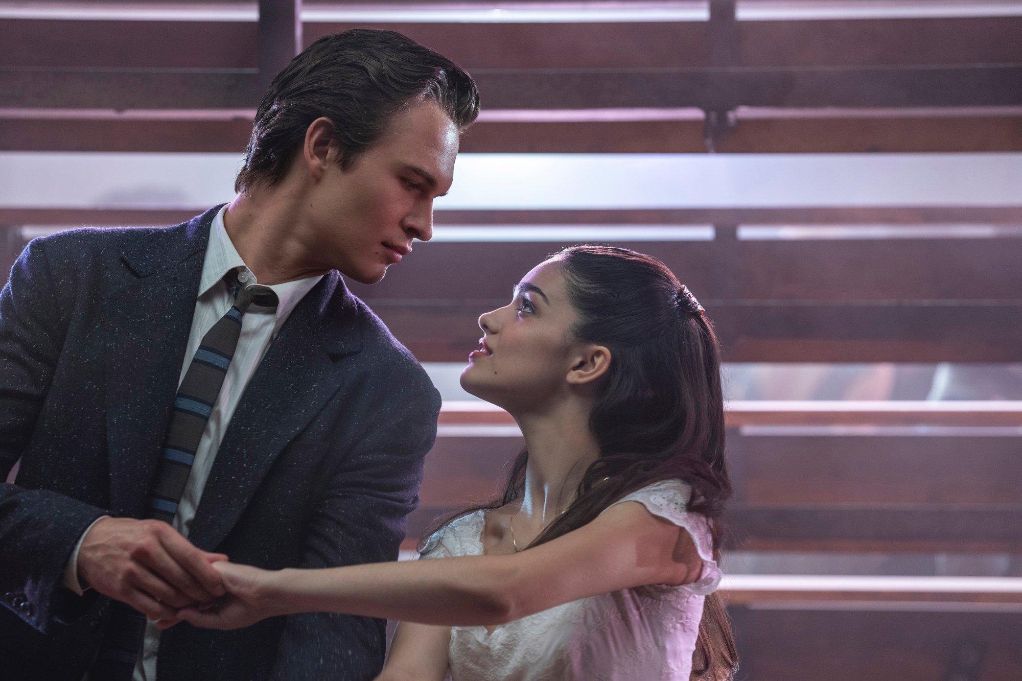 'West Side Story' movie review Ansel Elgort as Tony and Rachel Zegler as Maria holding hands under the bleachers