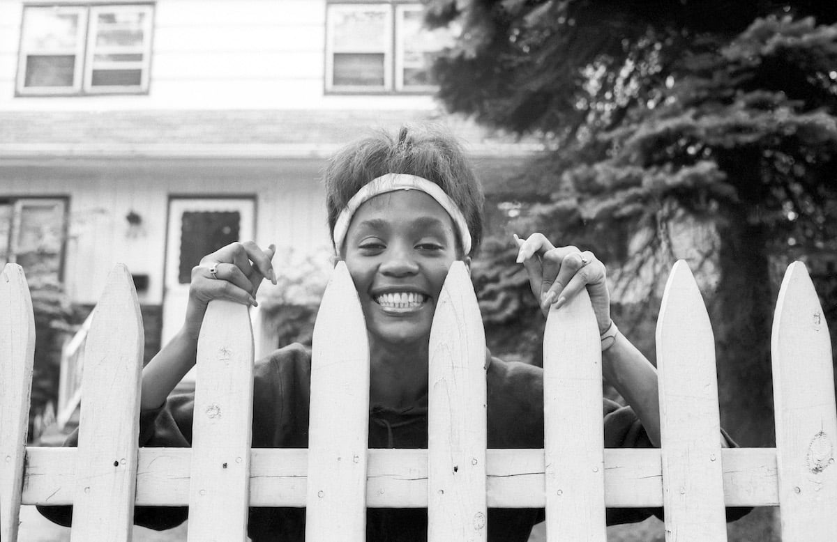 Whitney Houston smiles outside of childhood home