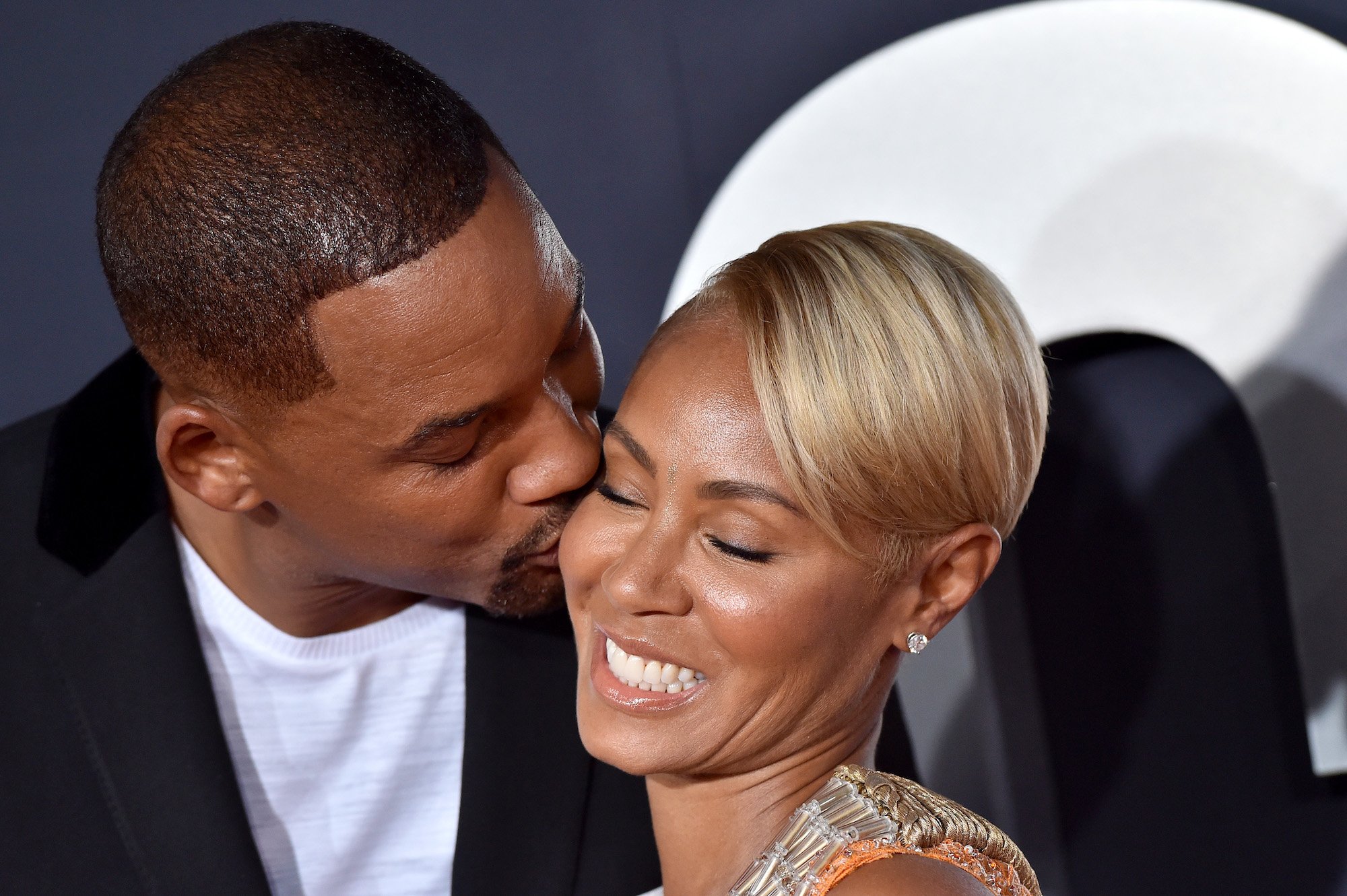 Will Smith kisses Jada Pinkett Smith on the cheek while she smiles