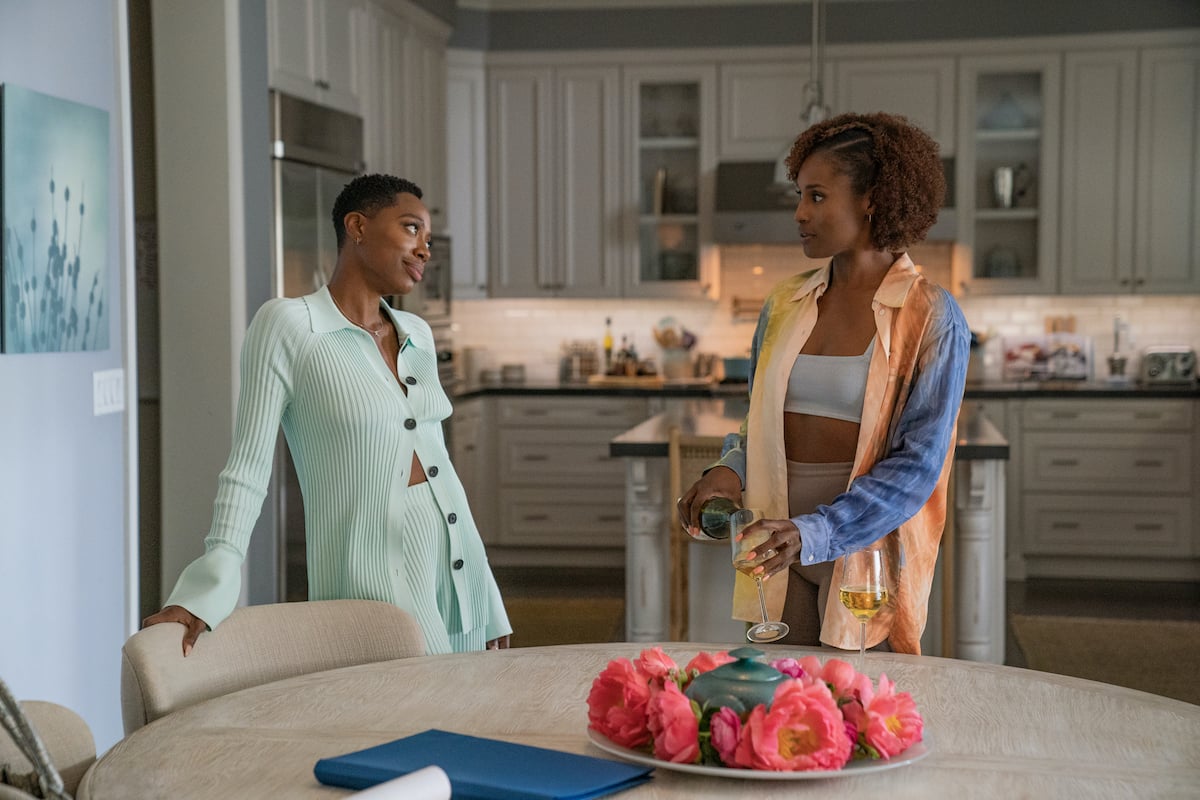 Issa Rae pouring a glass of wine while talking to Yvonne Orji in the 'Insecure' Season 5 finale.
