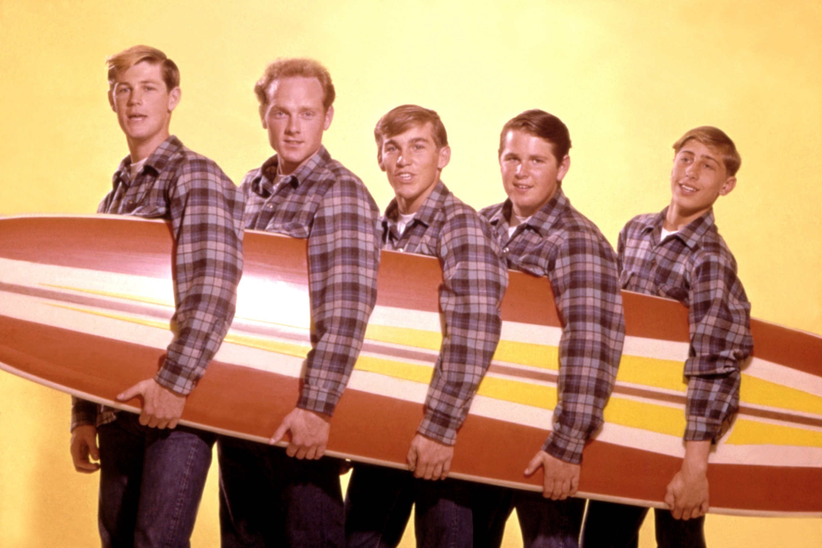 The Beach Boys' Brian Wilson, Mike Love, Dennis Wilson, Carl Wilson, and David Marks with a surf board